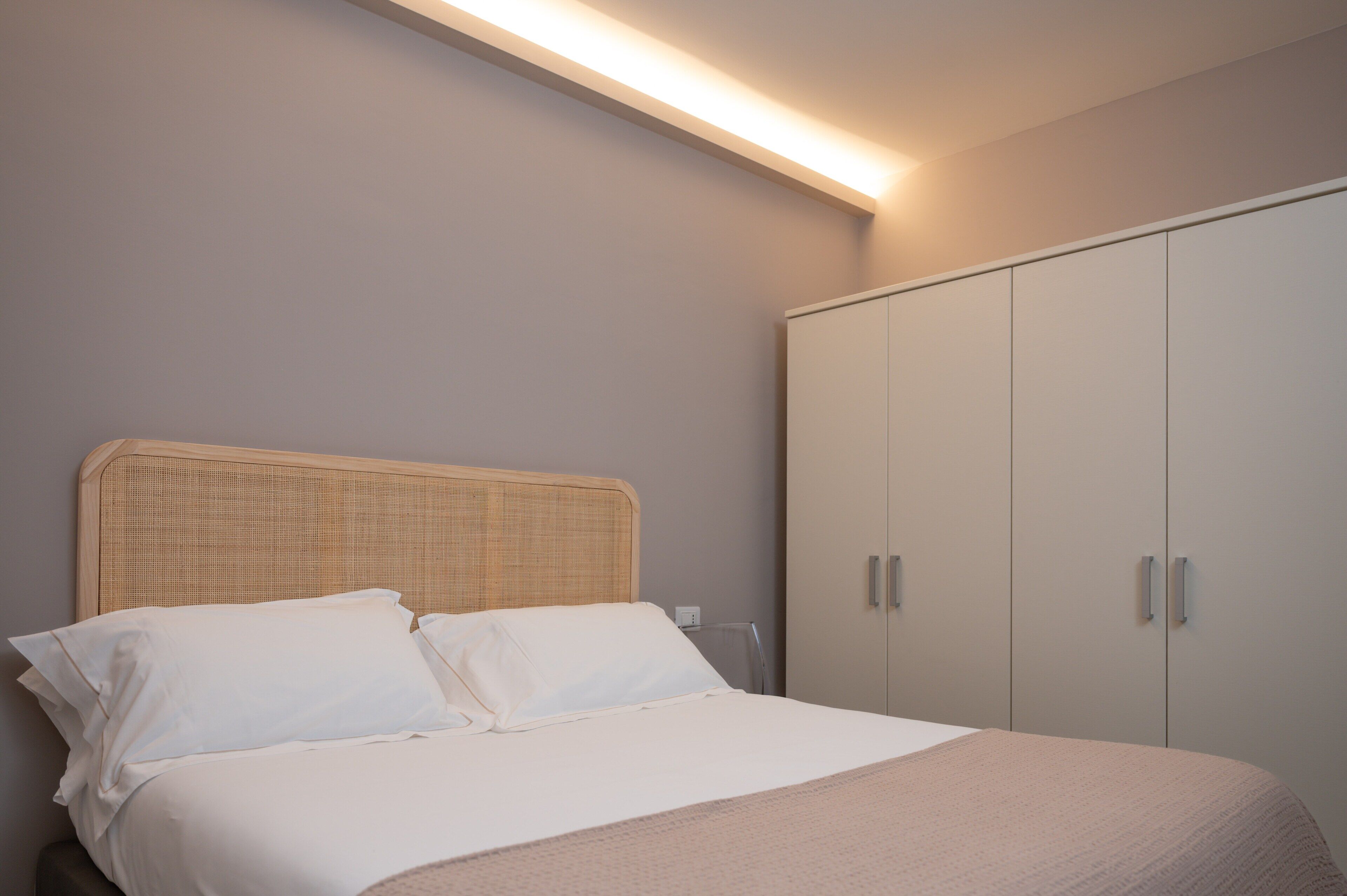 A bedroom with a bed, a wardrobe, and a ceiling light.