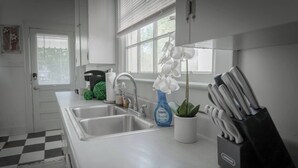 Een keuken met een dubbele spoelbak, een koffiezetapparaat, een plant en een messenblok.