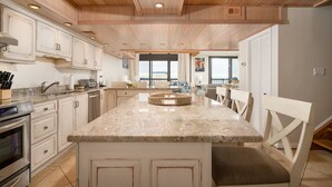 A spacious kitchen with wooden ceiling, granite countertops, and white cabinetry. - Exquisite 2 Story Penthouse with Spectacular Views of the Ocean and the Bay (Ocean City)