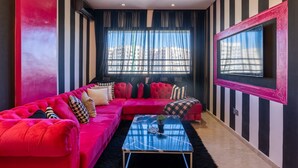 Una sala de estar moderna con un sofá rojo, una mesa de centro de vidrio y un televisor grande en la pared.