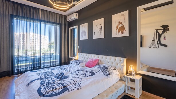 Un dormitorio con una cama grande, una mesita de noche con lámpara y cuadros en las paredes.