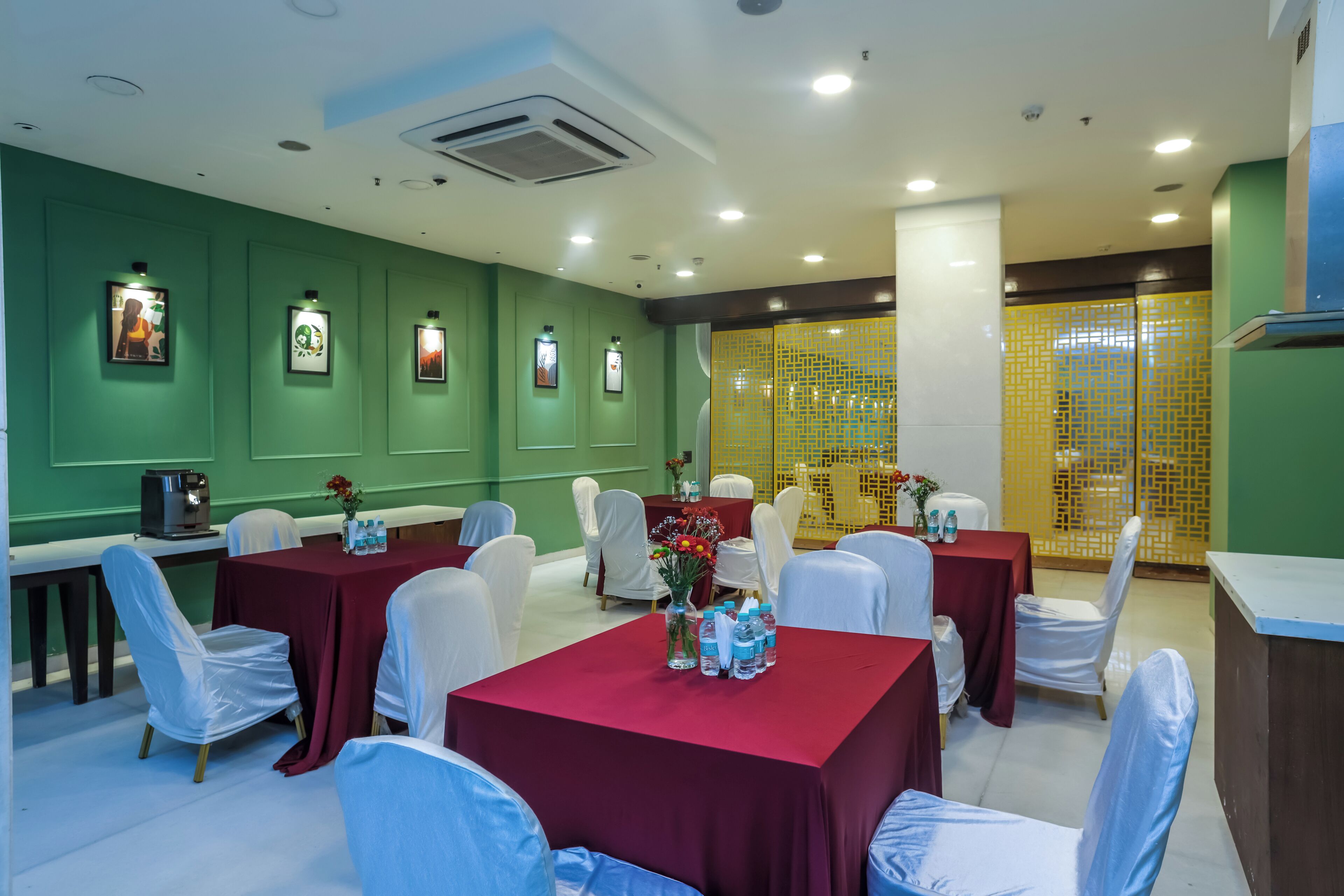 A conference room with tables and chairs, green walls, and framed pictures.