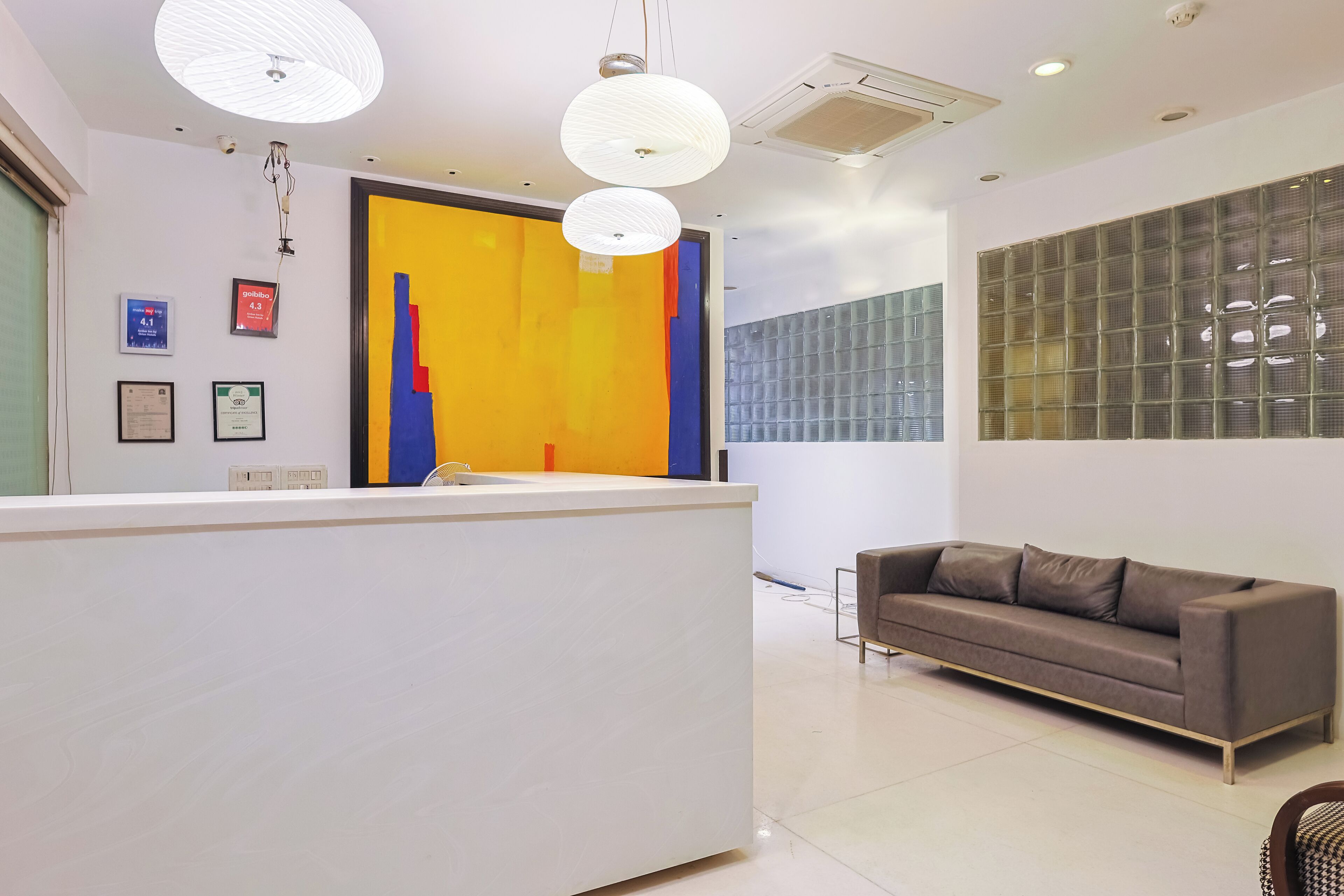 A modern reception area with a white reception desk, a brown sofa, and a colorful abstract wall art.