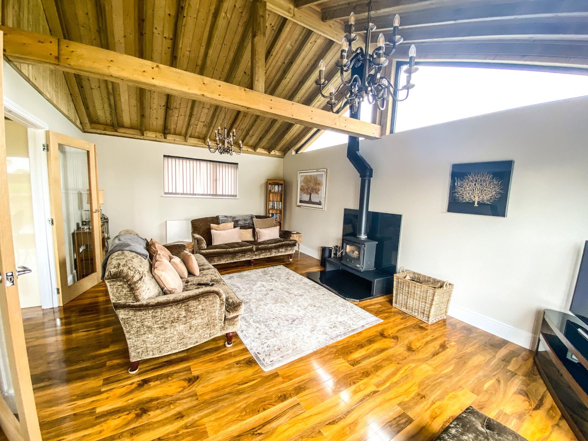 Uma sala de estar aconchegante com teto de madeira, lareira, sofá e estante de livros.