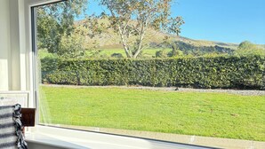 A room with a large window overlooking a grassy field and a tree. - Peaceful Rural Retreat with Mountain Views - Benbradagh Country Cottage (Dungiven)