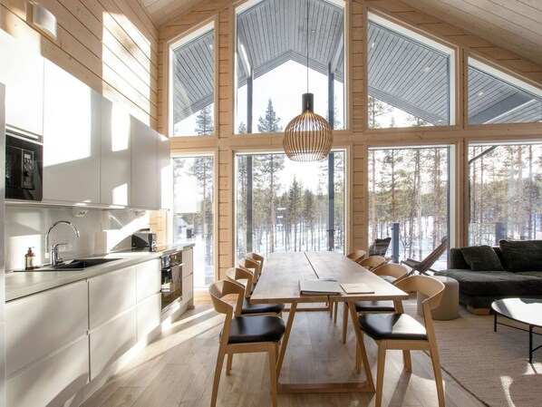 A modern interior with a large dining table, wooden chairs, and a kitchen area.