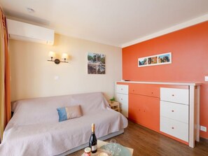 A bedroom with a bed, a nightstand, a dresser, and a wall-mounted light fixture.