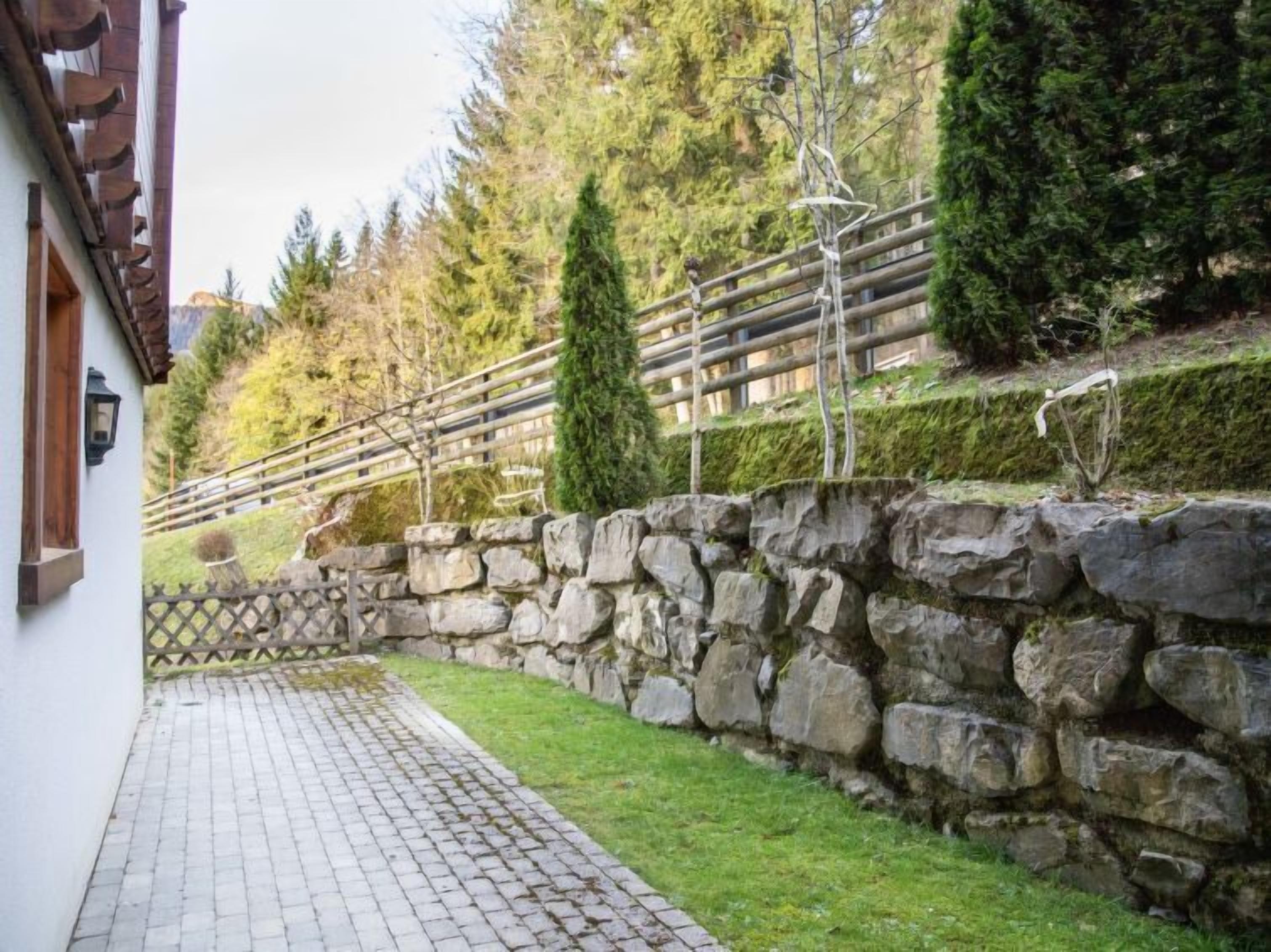 Um muro de pedra com um caminho pavimentado que leva a uma estrutura de madeira.