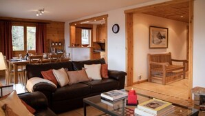 Ein gemütliches Wohnzimmer mit einer schwarzen Ledersofa, einem Glastisch und einem Essbereich mit Holzmöbeln.