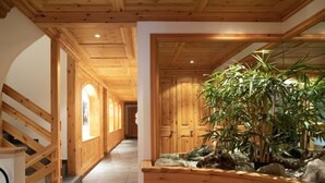 Ein Holzflur mit einer Treppe links und einer großen Pflanze rechts.