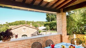A terrace with a table set for breakfast, overlooking a stone building and lush greenery. - Casa Graziani by Interhome (Città della Pieve)