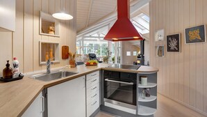 A modern kitchen with a built-in oven, a sink, and a red pendant light. - 2 bedroom amazing home in Slagelse (Slagelse)