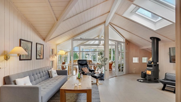 A spacious living area with a high ceiling, a fireplace, and a view through large glass doors to an outdoor patio. - 2 bedroom amazing home in Slagelse (Slagelse)