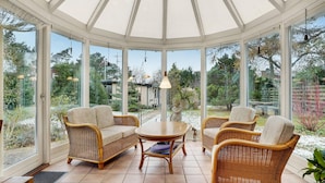 A conservatory with wicker furniture, large windows, and a view of the garden. - 2 bedroom amazing home in Slagelse (Slagelse)