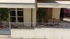 Un espace extérieur abrité, doté d’une rambarde en métal, de plantes en pot et d’une table et de chaises en bois.