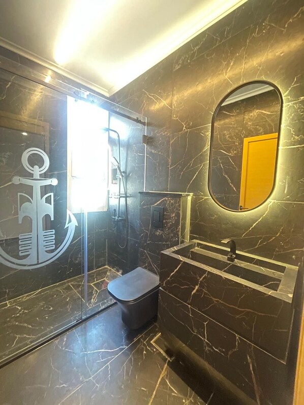 A bathroom with a marble floor, a toilet, a sink, and a shower. - Gondola marine resort (Halat)