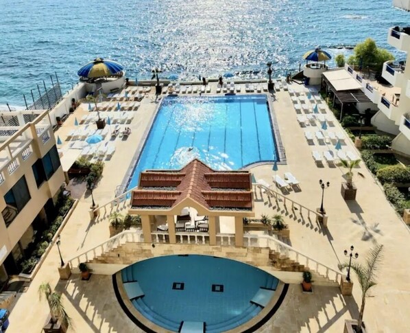 A rooftop pool with a clear view of the sea, surrounded by lounge chairs and umbrellas. - Gondola marine resort (Halat)