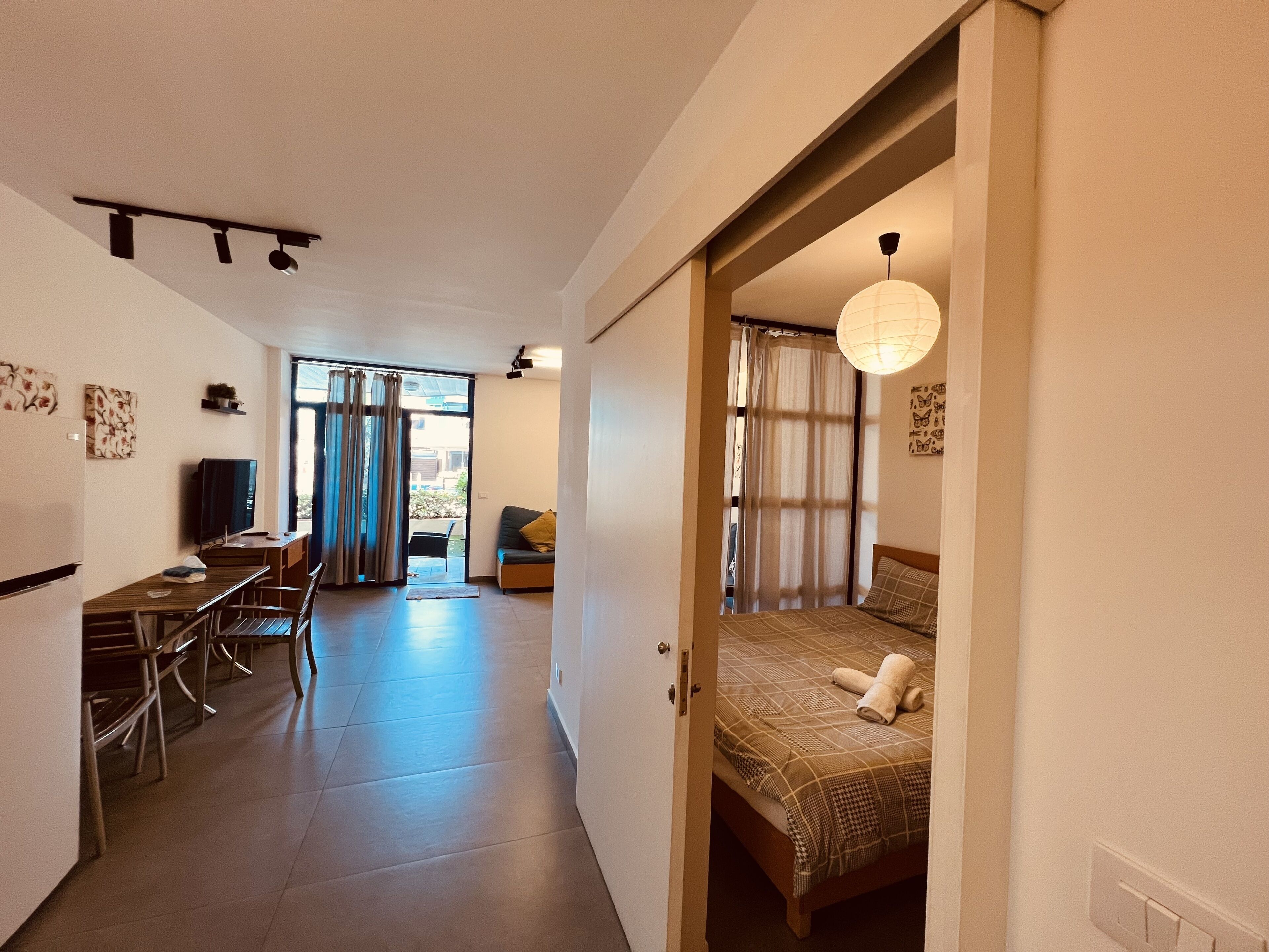 A modern, well-lit room with a bed, a desk, and a television.