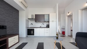 A modern kitchen with white cabinets, a built-in oven, and a coffee maker. There is a dining table with a bottle of wine and a glass. - Villa Julija Zadarvillas (Sukosan)