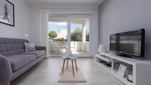 A modern living room with a grey sofa, a flat-screen TV on a white stand, and a glass door leading to an outdoor patio. - Villa Julija Zadarvillas (Sukosan)