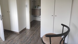 A room with a wooden floor, a white wardrobe, and a chair. - Buena Ubicación 2 Dormitorios 2 Baños (Puerto Montt)