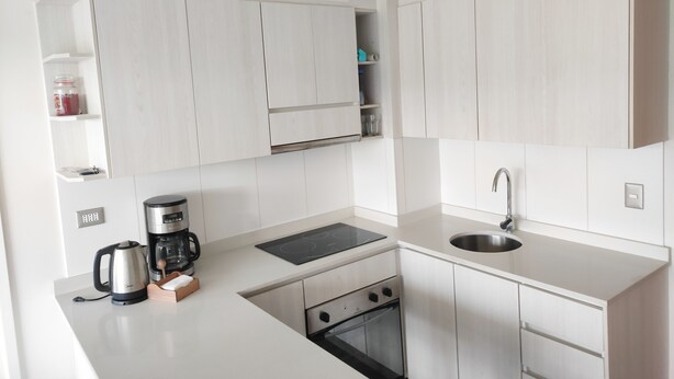 A modern kitchen with white cabinetry, a built-in oven, a stovetop, and a sink. - Buena Ubicación 2 Dormitorios 2 Baños (Puerto Montt)