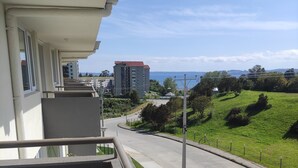 A balcony with a view of a road, greenery, and buildings in the distance. - Buena Ubicación 2 Dormitorios 2 Baños (Puerto Montt)