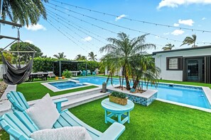 Un patio trasero con piscina, una hamaca y mobiliario de exterior.