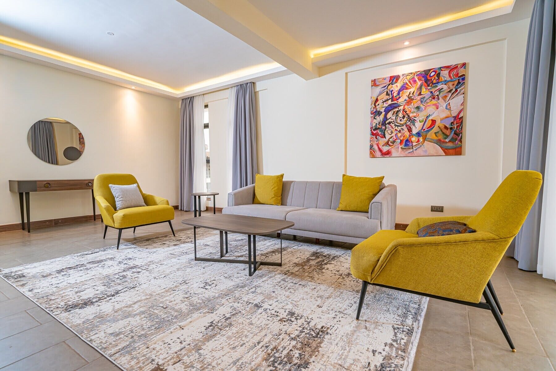 A modern living room with a sofa, two armchairs, a coffee table, and a painting on the wall.