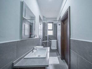 Un bagno stretto con lavandino, specchio e doccia.
