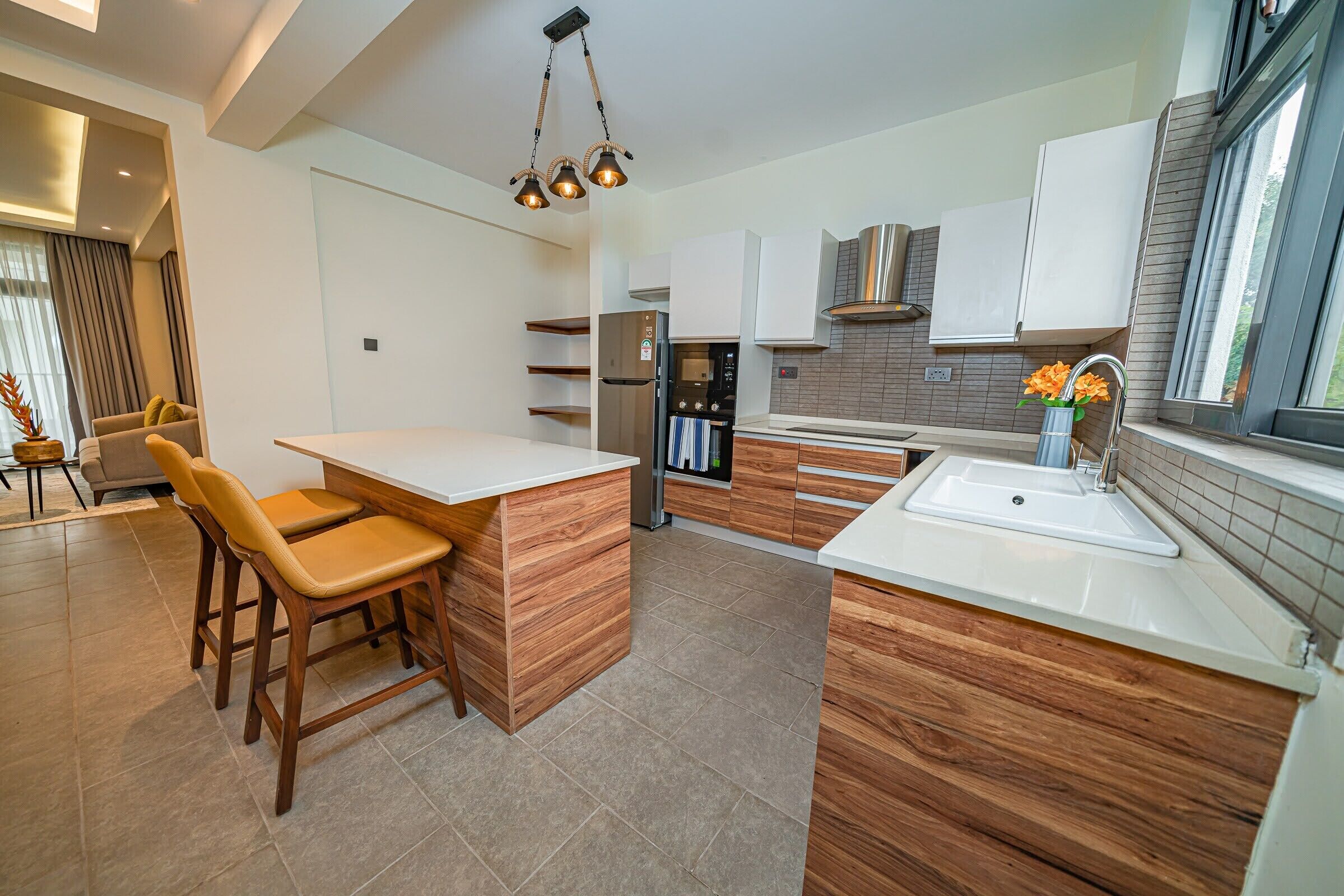 A modern kitchen with wooden cabinetry, a central island, and a built-in oven.