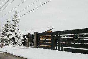 A snow-covered gate with a wooden fence, a metal gate, and a building in the background. - Serene Lake Getaway at Stunning Scandi Home (Coeur d'Alene)