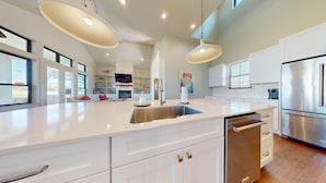A modern kitchen with a large island, stainless steel appliances, and ample natural light. - River City Resorts: Oxbow House, on the Guadalupe River (New Braunfels)