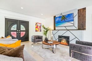 A modern living room with a fireplace, comfortable seating, and artwork on the walls.