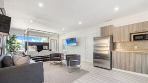 Ett modernt hotellrum med en säng, en soffa och en liten sittgrupp. Det finns även ett litet pentry med kylskåp och mikrovågsugn.