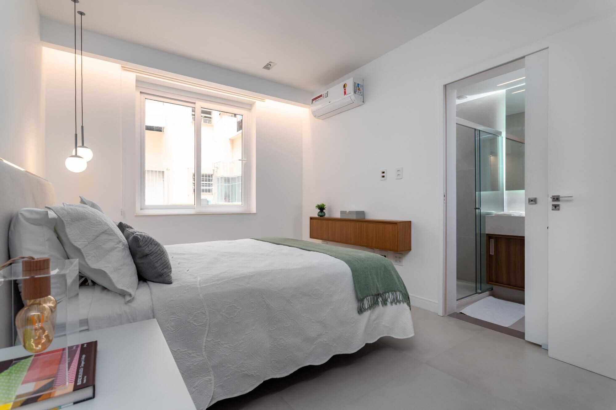 A bedroom with a bed, bedside table, lamp, window, and built-in wardrobe.