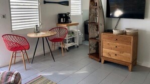 A compact living space with a dining area, a TV mounted on the wall, and a small wooden cabinet. - Sea Breeze - An Intimate Villa Rental Overlooking Leverick Bay. (Virgin Gorda)