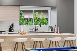 Une cuisine moderne avec une grande fenêtre, un évier et des tabourets de bar.