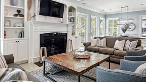 A spacious living room with a fireplace, a large TV, and comfortable seating. - 5 Sandy Beach Trail- Beach House w/ Private Pool (Hilton Head)