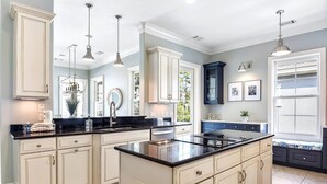 A spacious kitchen with white cabinetry, black countertops, and pendant lighting. - 5 Sandy Beach Trail- Beach House w/ Private Pool (Hilton Head)