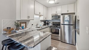A modern kitchen with white cabinets, stainless steel appliances, and a granite countertop.