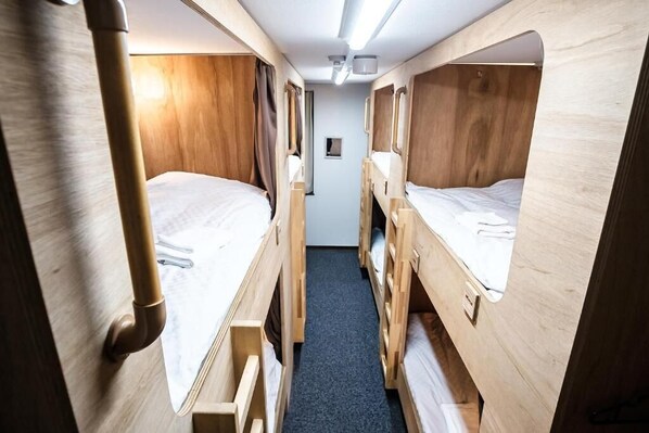 A narrow corridor with bunk beds on either side, wooden walls, and a carpeted floor. - Stay Osaka Namba (Osaka)