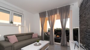 A modern living room with a sofa, a coffee table, and a TV. - Villa Magnifica Apartments with pool (Novalja)
