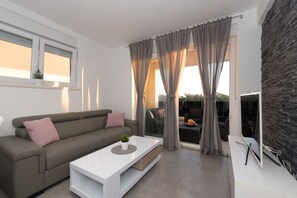 A modern living room with a sofa, a coffee table, and a TV. - Villa Magnifica Apartments with pool (Novalja)