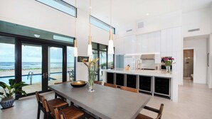 A modern kitchen with a large island, white cabinetry, and pendant lighting.