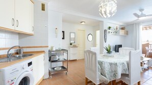 Una cucina moderna con lavatrice, un'area pranzo con tavolo e sedie, e una ventola a soffitto.