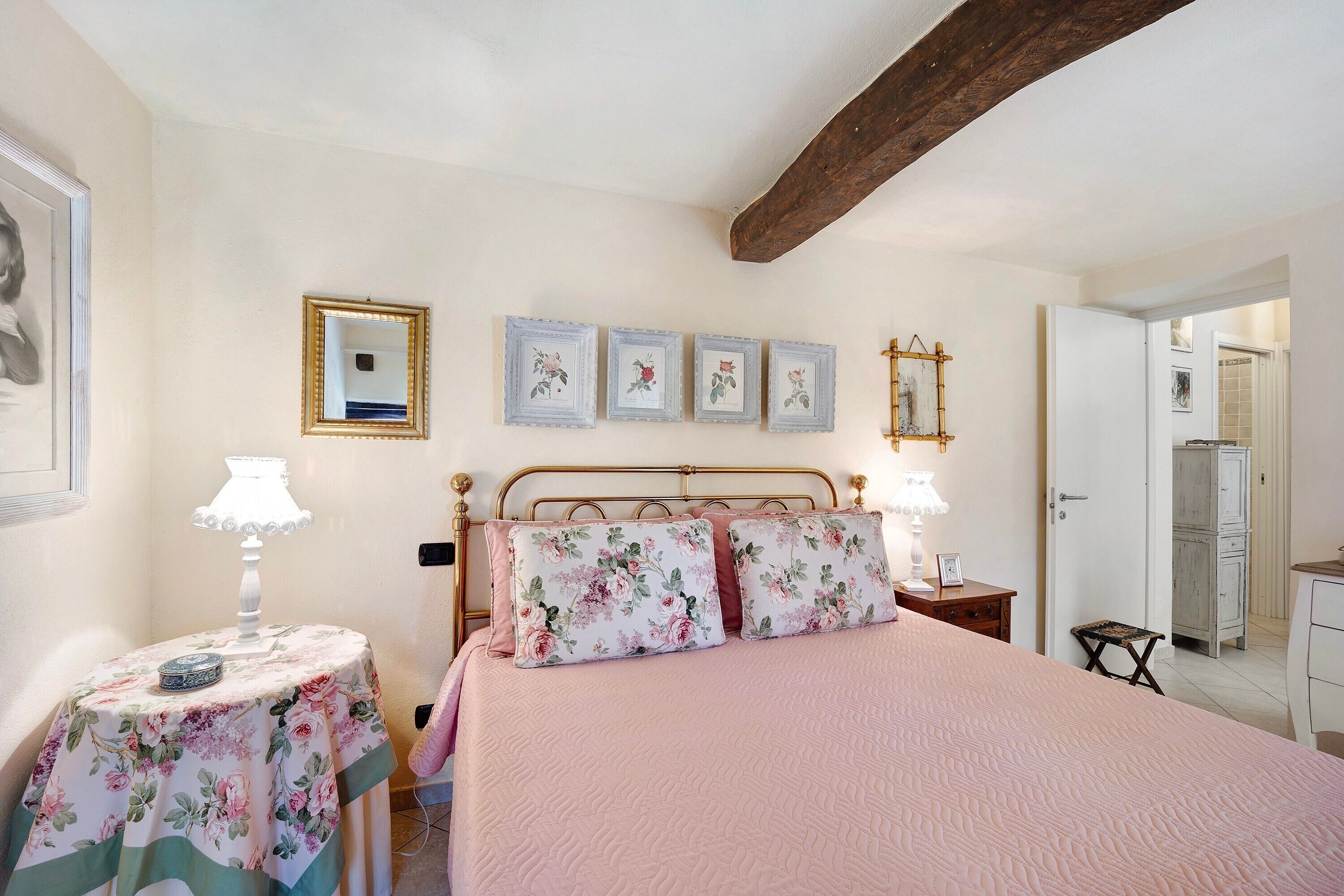 Une chambre à coucher comprenant un lit, des tables de chevet, un miroir et une porte donnant sur une salle de bain.