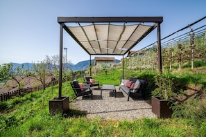 Un espace extérieur aménagé avec une pergola, un canapé, deux fauteuils et une table.