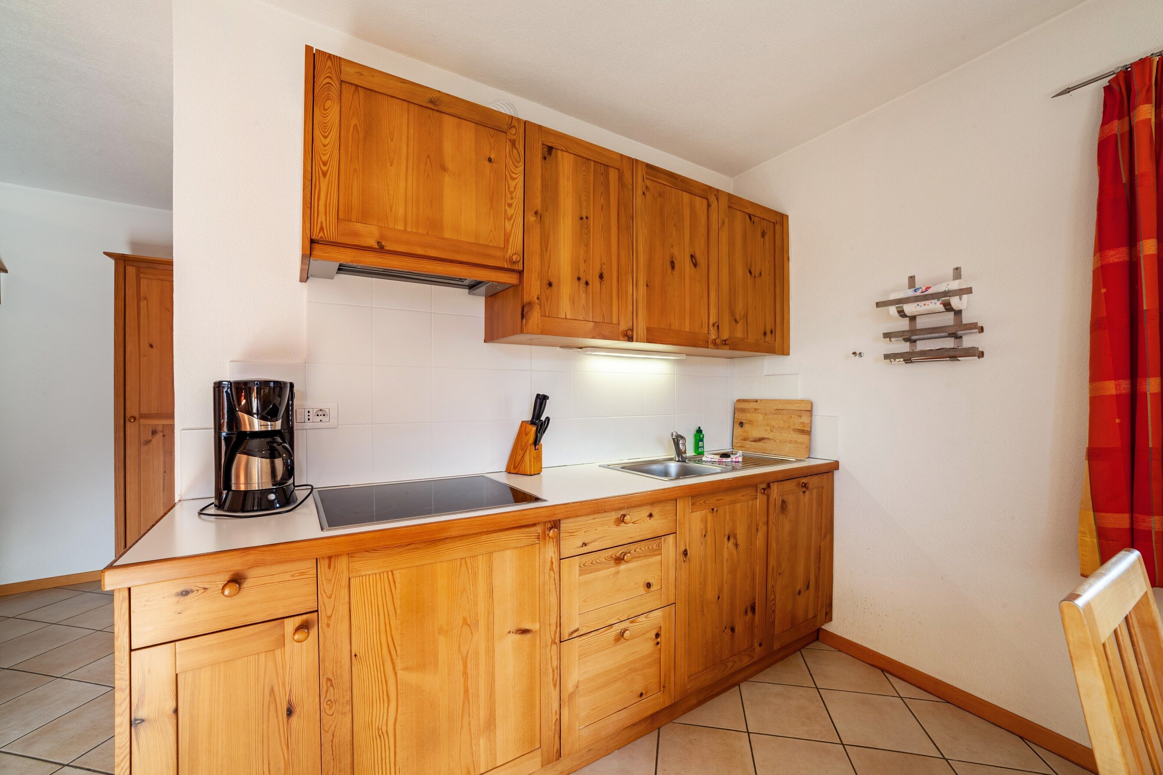 A kitchen with wooden cabinets, a coffee maker, a knife block, and a sink.