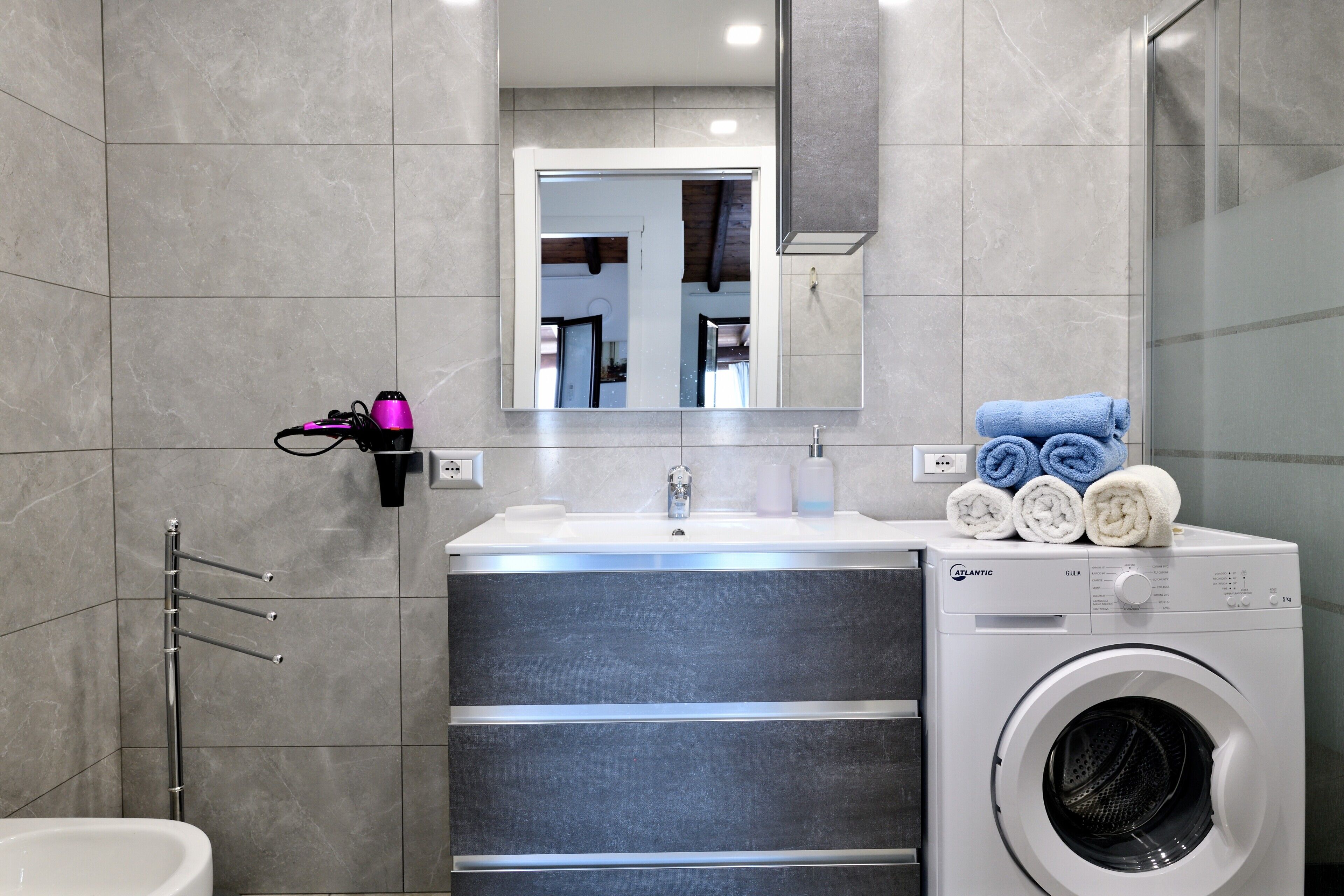 Un baño moderno con lavadora incorporada, un espejo y un perchero para toallas.
